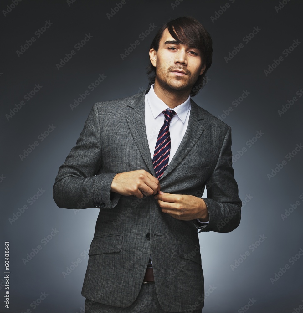 Attractive businessman getting dressed on black background