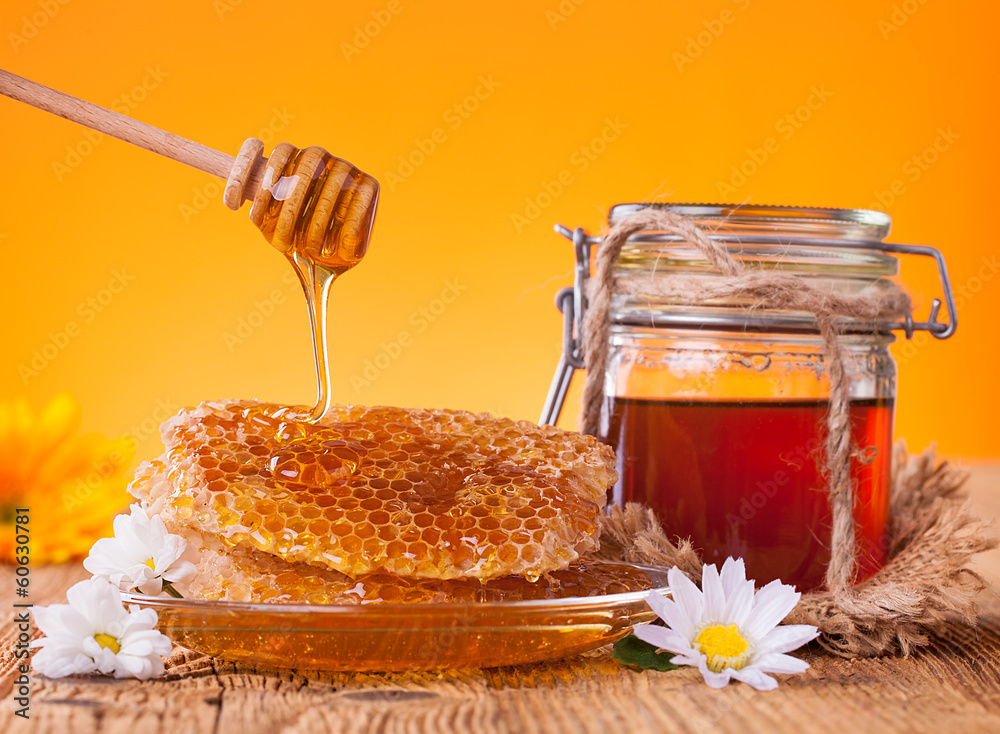 Honey in jar with honeycomb and wooden drizzler