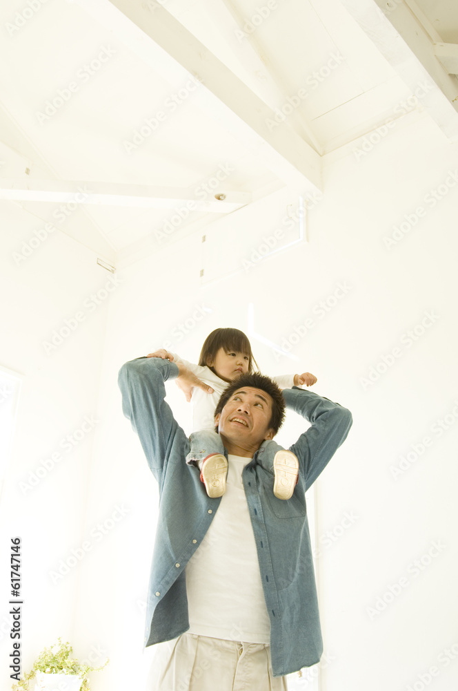 Japanese father carrying daughter on his shoulders indoors