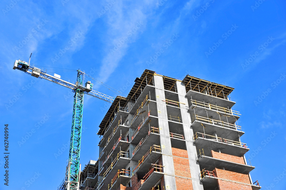 Crane and building construction site against blue sky