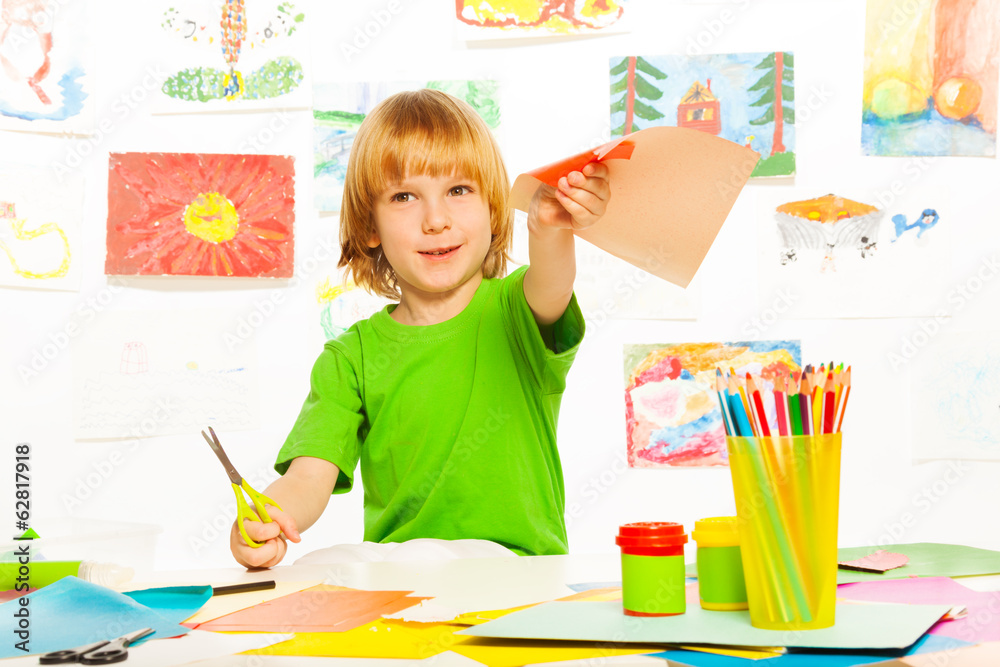 Blond boy cutting color paper