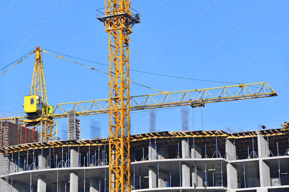 Crane and building construction site against blue sky