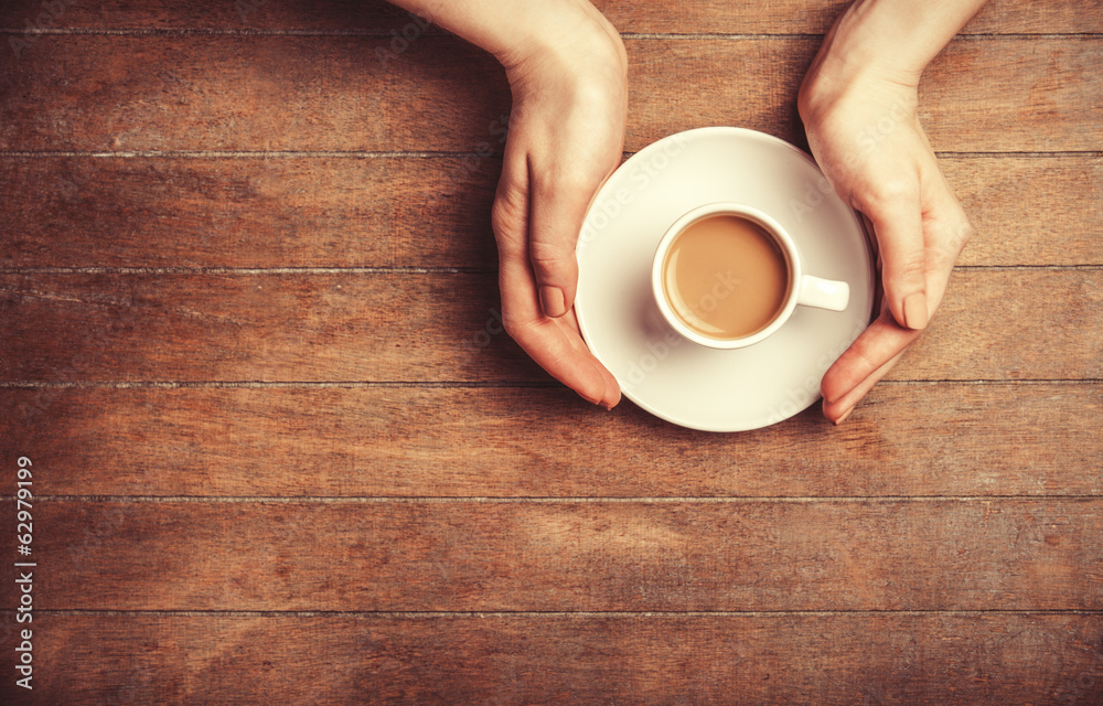 Female hands holding cup of coffee.