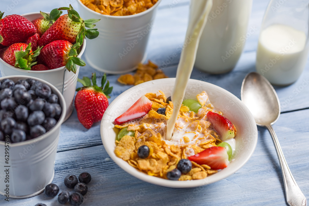 Pouring milk into cornflakes with fruits