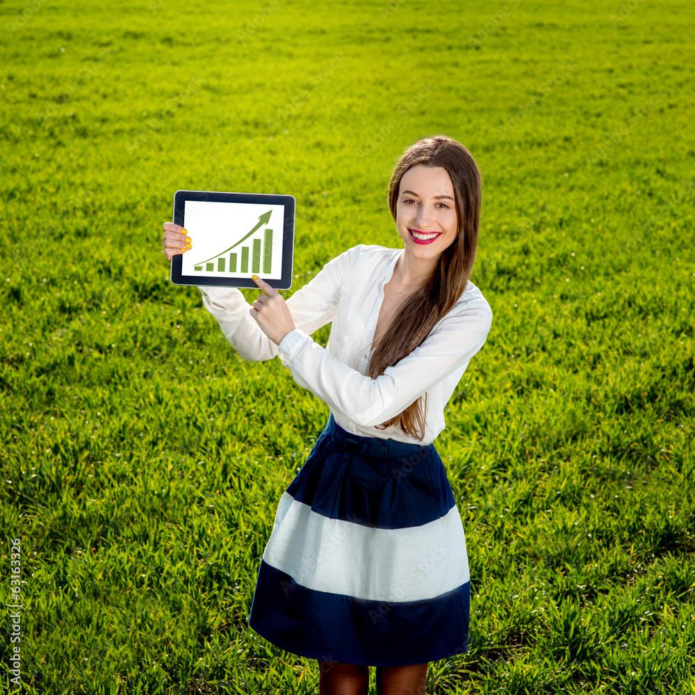 Young woman showing growth diagram on the tablet on the green fi