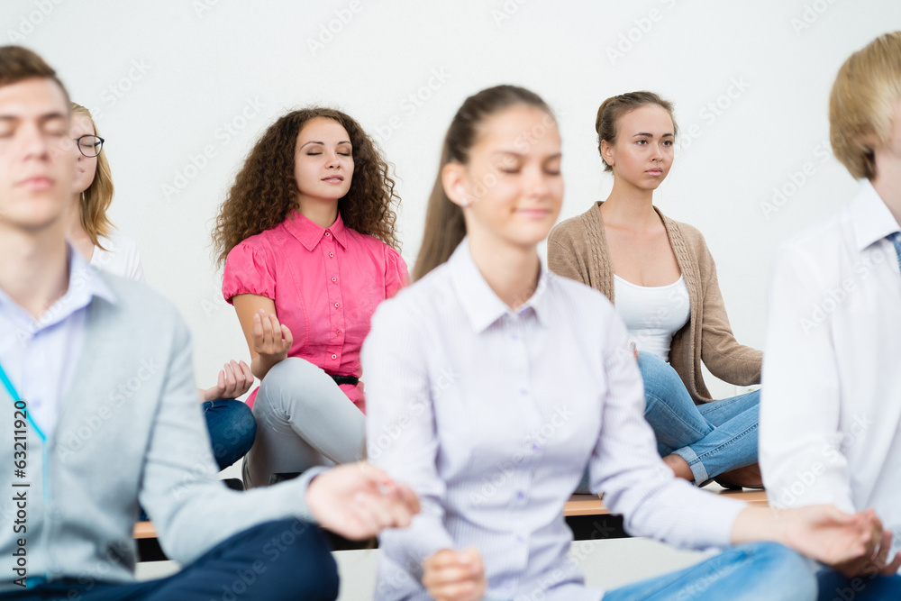 group of young people meditating