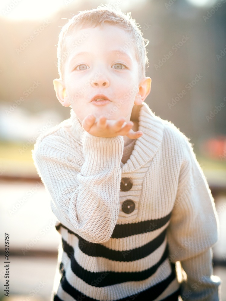 Child blowing kiss, little boy playing outdoor