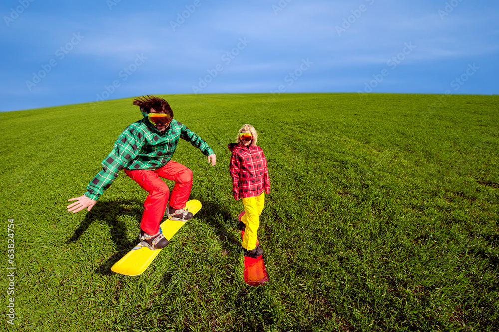 Young couple in sport wear snowboarding on the grass in the gree