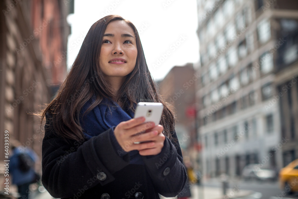 年轻的亚洲女人在街上发短信