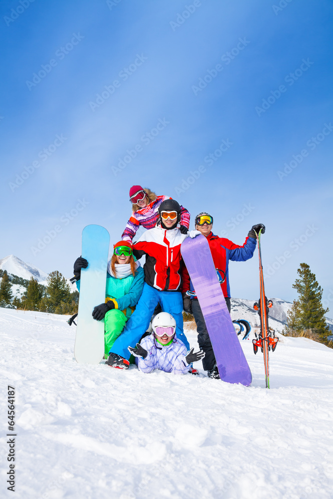 Happy friends posing with snowboards and skis