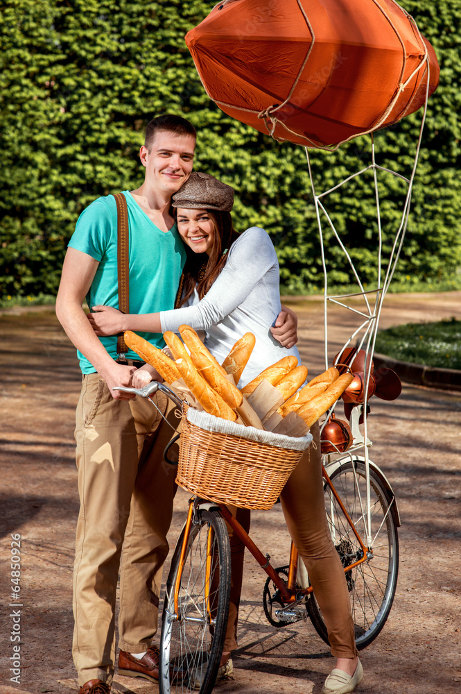 Young and joyful couple hugging in the park with bicycle and air