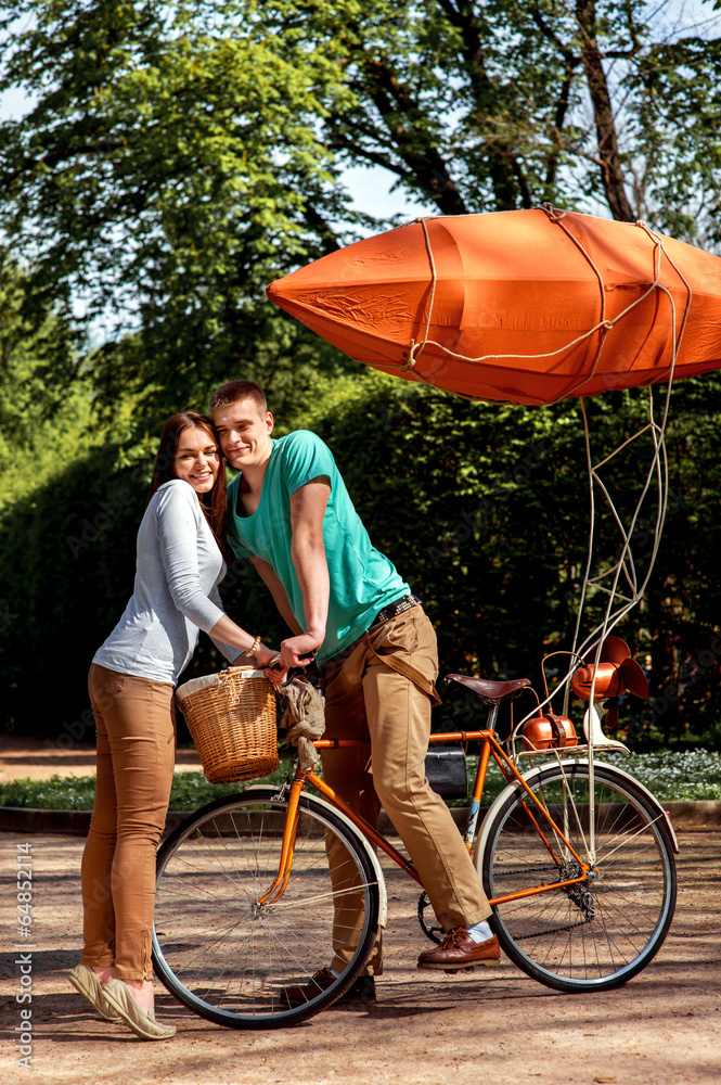 Young and joyful couple hugging in the park with bicycle and air