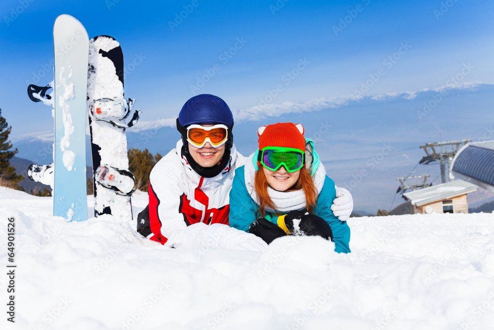 Hugging couple in ski masks lying on the snow