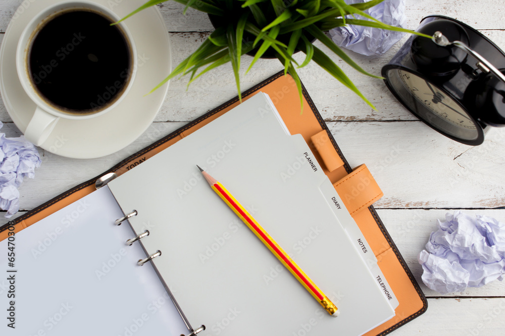 Top view of coffee on office table with notebook and pencil