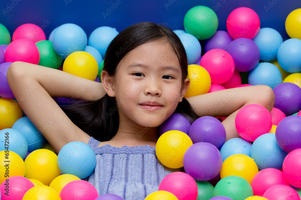 Happy Asian child playing at kindergarten with colorful balls