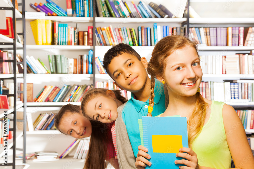 Four children standing in a row inside library