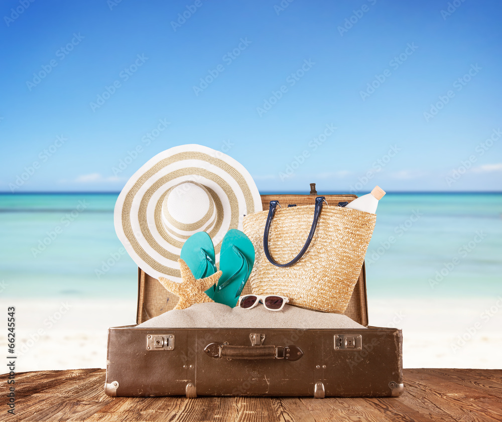 Old suitcase with accessories on beach