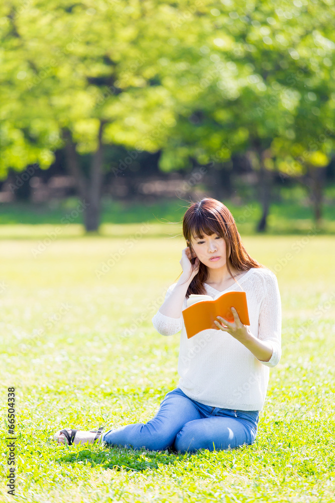 亚洲年轻女子在公园看书