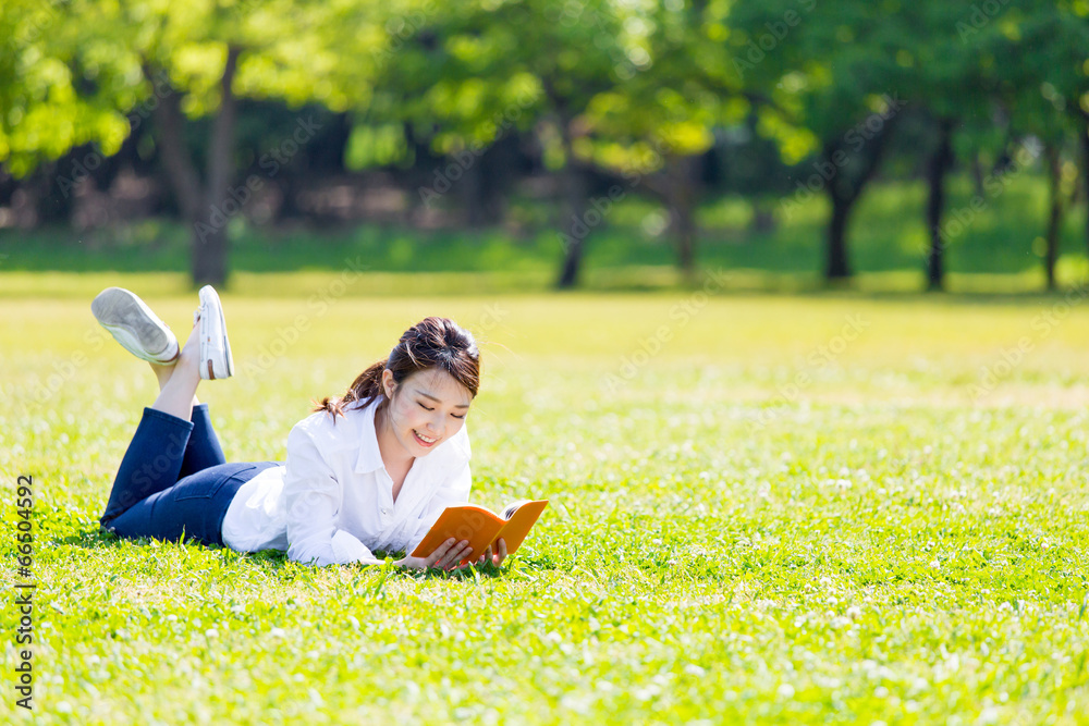 young asian woman reading book in the park