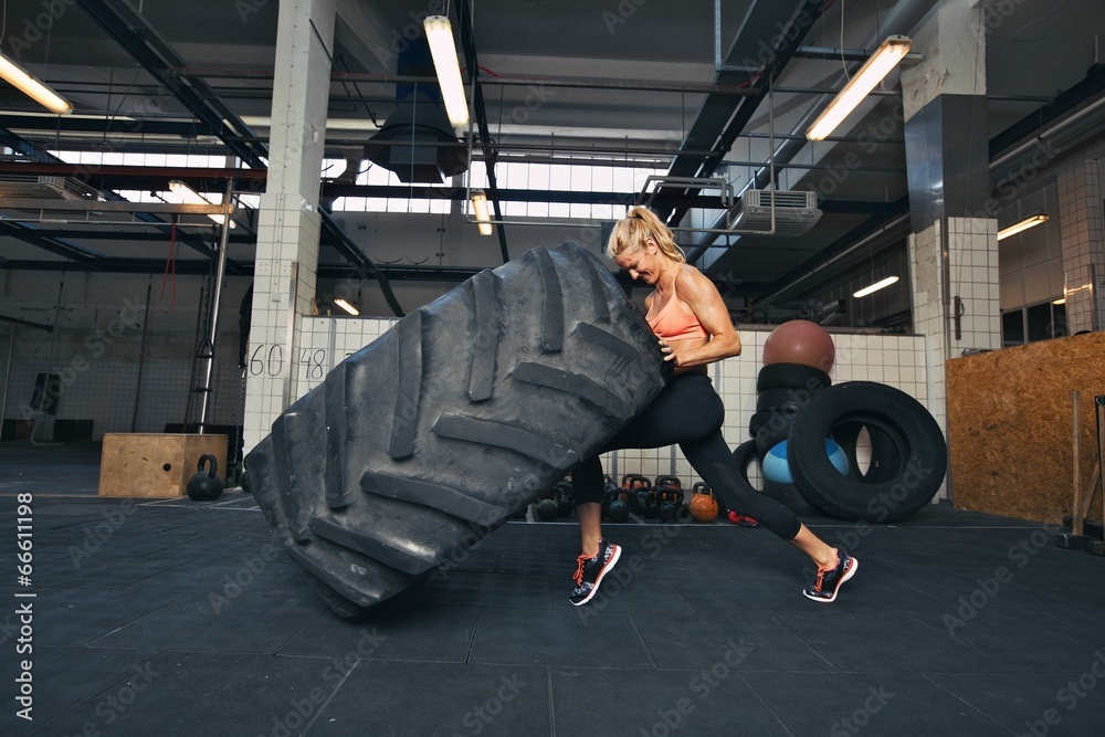 Crossfit女子在健身房翻大轮胎