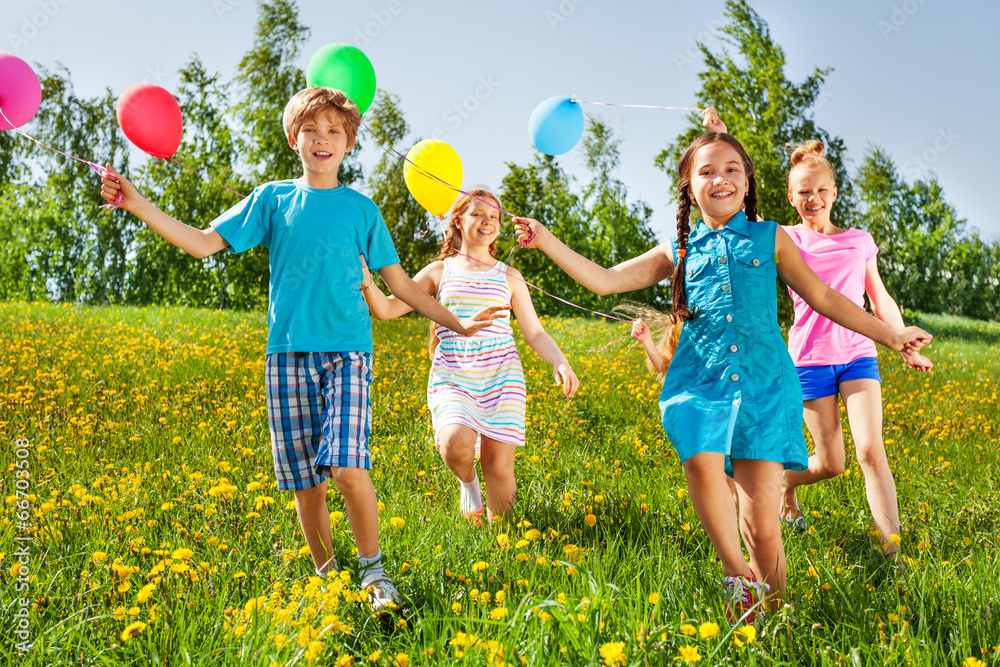 Running happy kids with balloons in green field