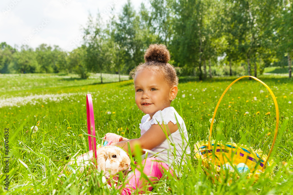 Curly cute girl with rabbit in green park