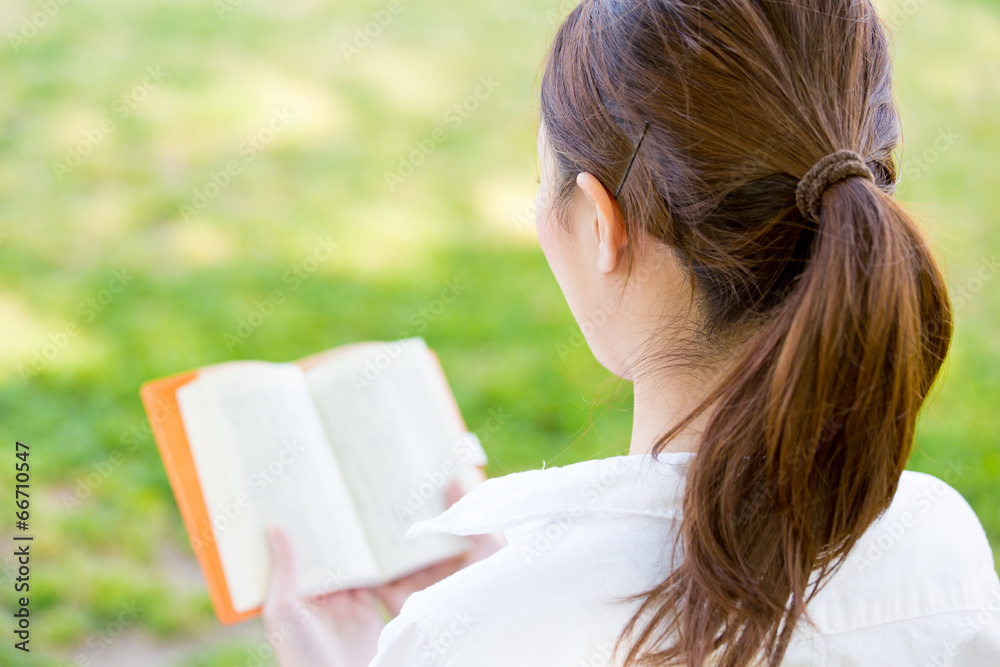 young asian woman reading book in the park