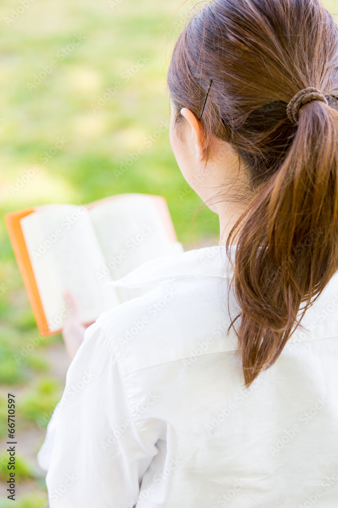 young asian woman reading book in the park