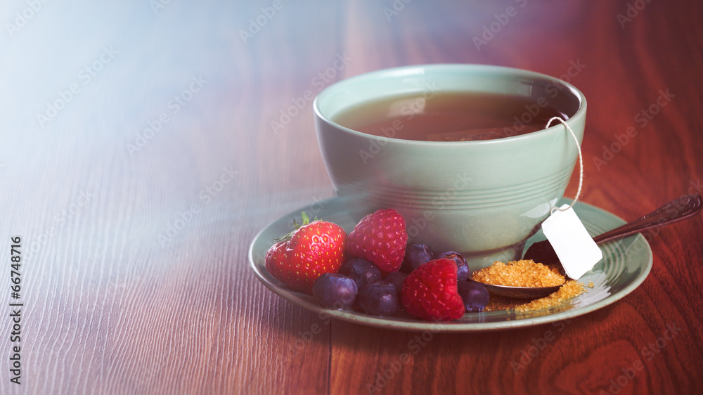 Cup of fruit tea with berries on wooden table with copy space