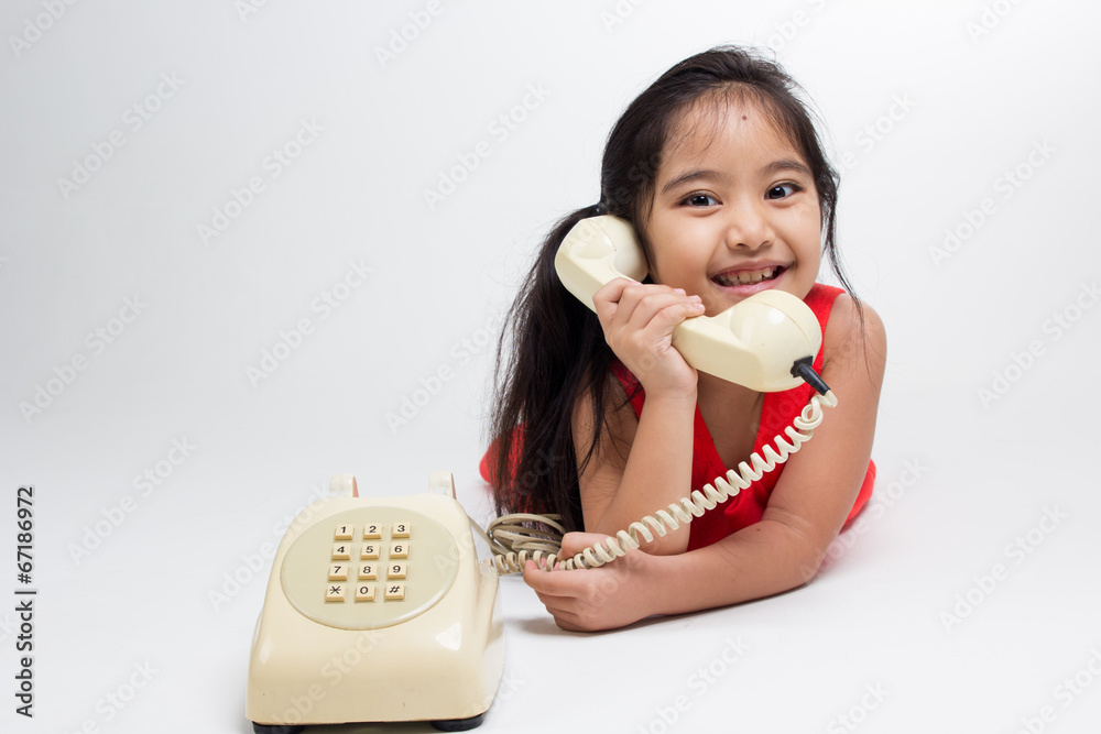 Happy little Asian child in red dress with telephone