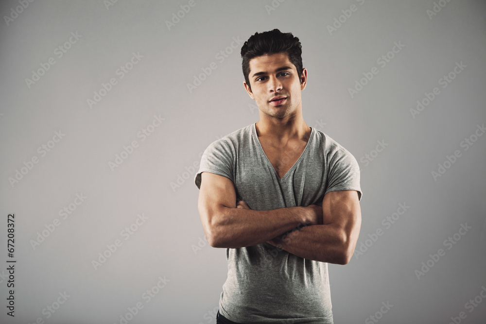 Young muscular man posing against grey background