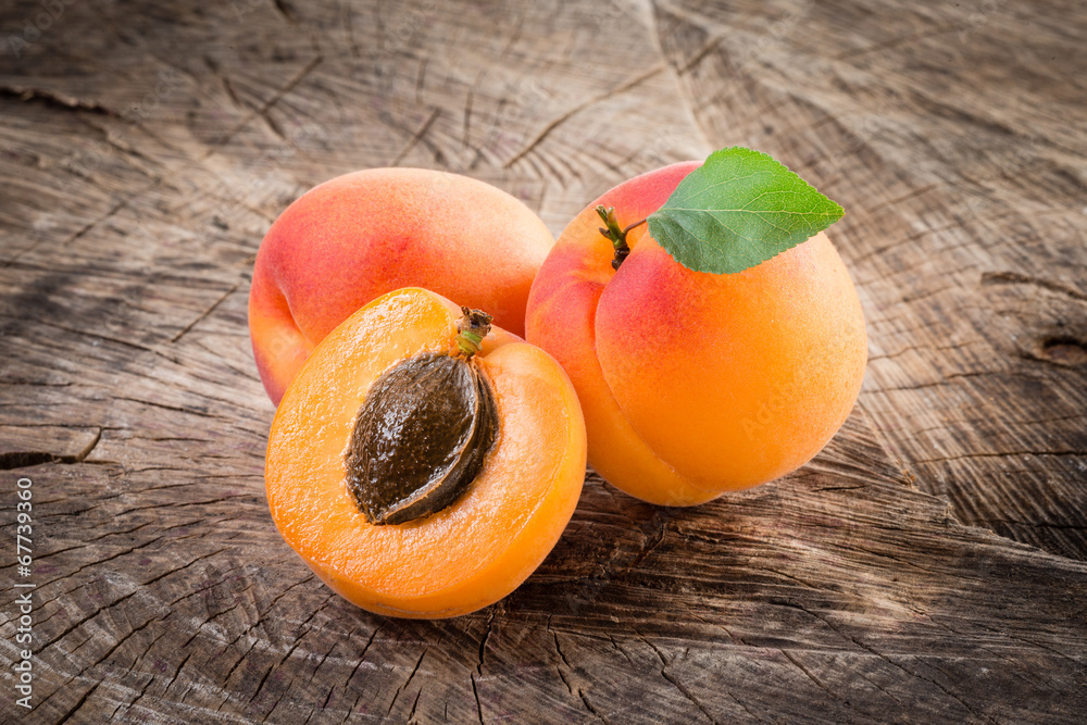 Apricots with leaves on wooden background