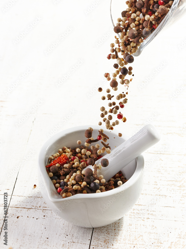 various spices falling into mortar and pestle