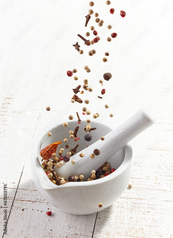 various spices falling into mortar and pestle