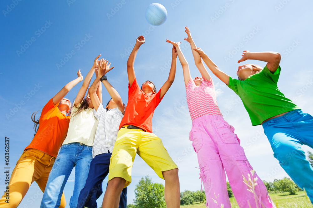 Happy kids playing with ball jumping in air