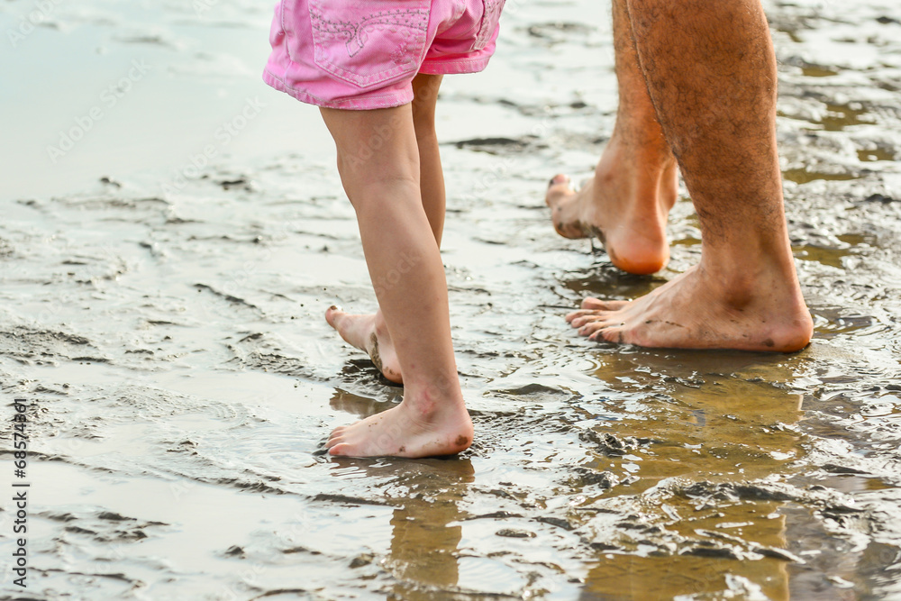 legs of a father and son walking on the beach