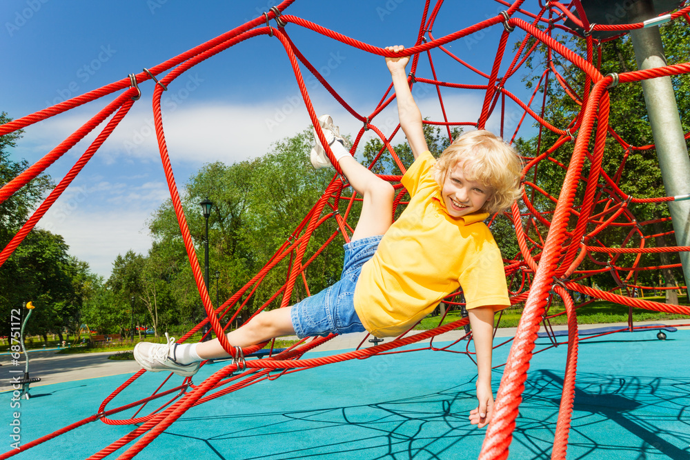 Boy hangs with legs and arms hold the ropes