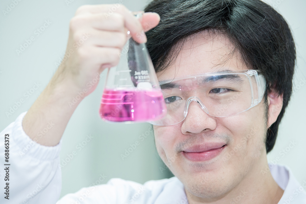 Asian scientist working in the lab,examines a test tube with liq