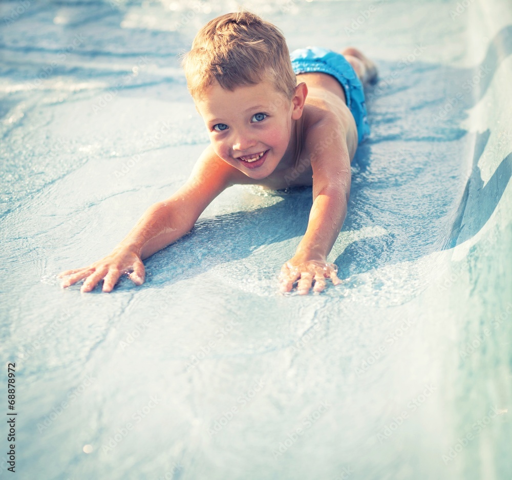 Child on water slide at aquapark, summer holiday