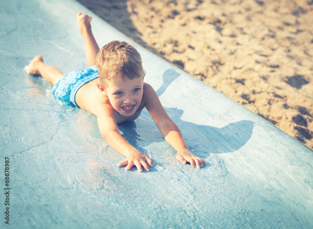 Child on water slide at aquapark, summer holiday