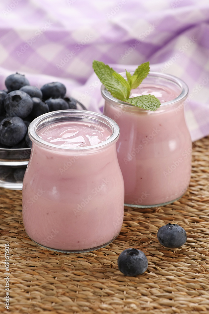 yogurt with blueberries in a glass jar and blueberries in a glas