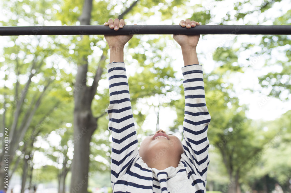 Boy hanging on horizontal bar