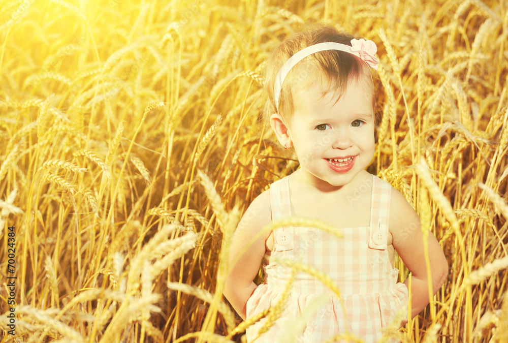 happy little girl in a field of golden wheat in the summer