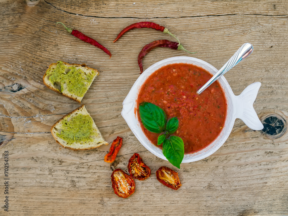 A bawl of tomato soup on a wooden desk