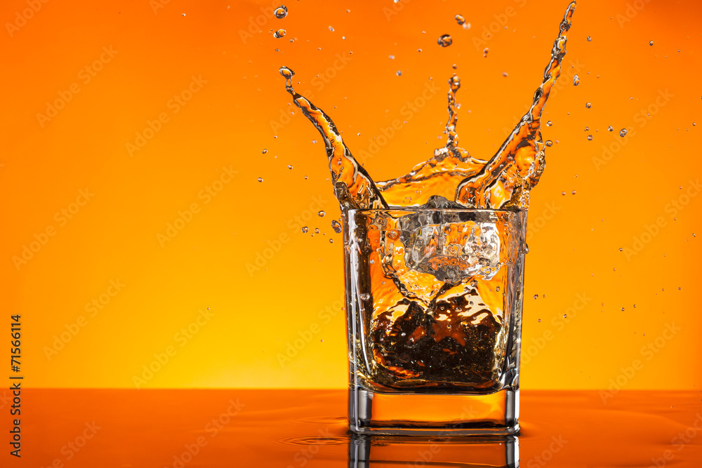 Whiskey drink splashing out of glas