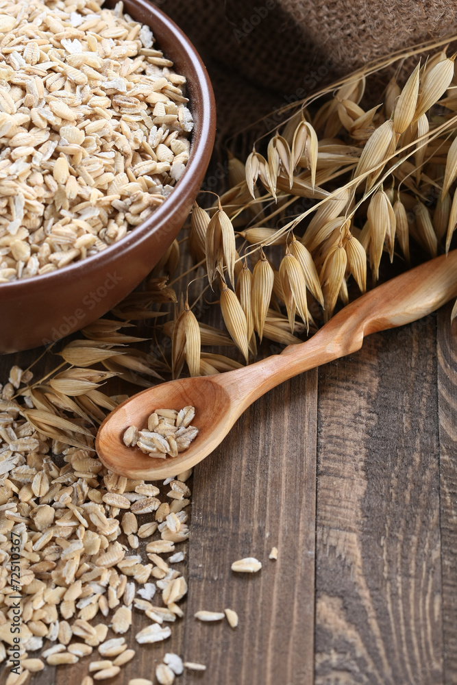 oatmeal in a clay bowl, stalks of oats on the background of wood