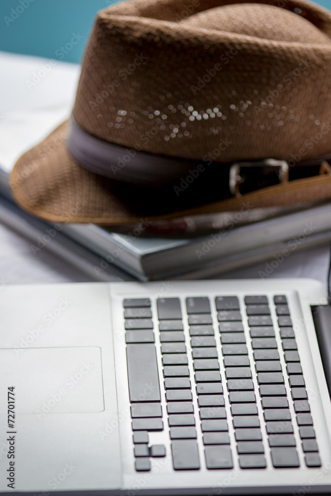 Sun hat and laptop on the bed, travel concept