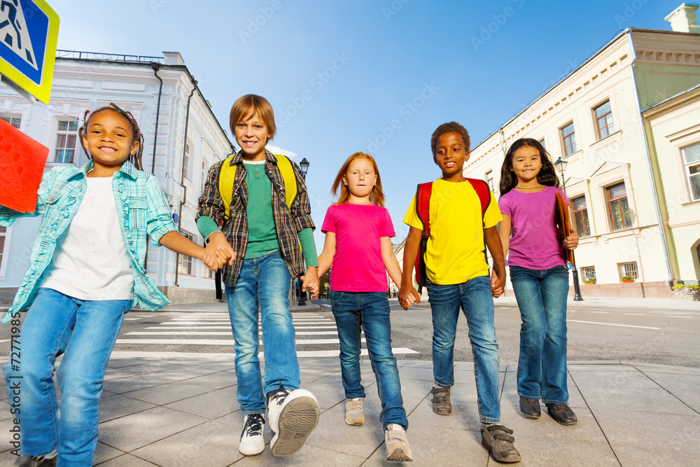 International children wear bags and walk in row