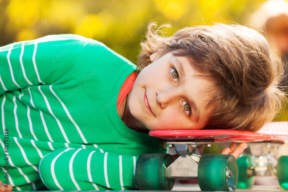 Portrait of boy with his head on skateboard