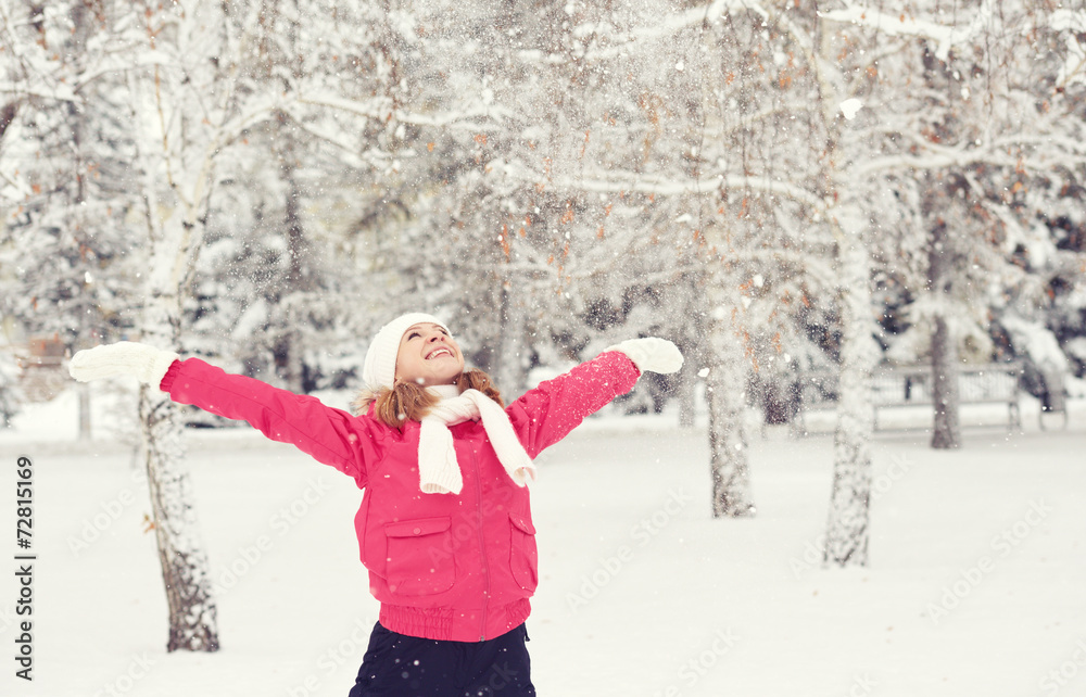 happy girl enjoying life and throws snow at winter outdoors